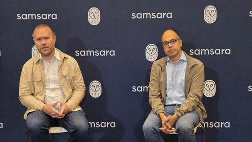 Two men sit during a panel discussion with Samsara logos displayed behind them